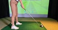 Professional female golfer playing golf indoors on golf simulator closeup Royalty Free Stock Photo