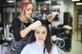 Professional female hairdresser applying color to female customer at design hair salon, woman having her hair dyed Royalty Free Stock Photo