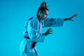 Professional female judoist training isolated on blue studio background in neon light. Healthy lifestyle, sport concept. Royalty Free Stock Photo