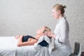 Professional female masseur giving relaxing massage treatment to young female client. Hands of masseuse on forehead of Royalty Free Stock Photo