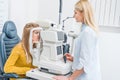 professional female oculist examining patient through slit lamp