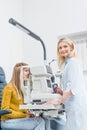 professional female optometrist examining patient through slit lamp Royalty Free Stock Photo