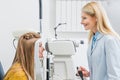 professional female optometrist examining patient through slit lamp Royalty Free Stock Photo