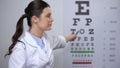 Professional female optometrist showing letters on eyechart, sight examination