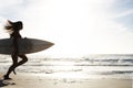 Professional female surfer going for surfing. Portrait of a young female running with a surfboard towards sea. Royalty Free Stock Photo