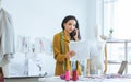 Professional female tailor wearing modern suit, working, seriously talking mobile phone, receiving complaint from customers, Royalty Free Stock Photo