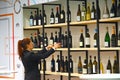 Professional female waiter at winery arranging bottles on shelf to offer tastings to enthusiasts