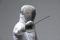 Professional fencer in fencing mask attacking on grey background Royalty Free Stock Photo