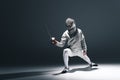 Professional fencer in fencing mask with rapier standing in position