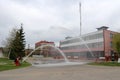 Professional firefighters in orange fire-resistant suits in white helmets with gas masks are testing fire hoses and fire guns to e