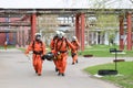 Professional firefighters rescuers in orange protective fire-resistant suits, white helmets and gas masks bear the injured person