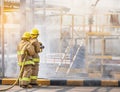 Professional firemans brave buddy team assistance in yellow fire fighter uniform holding fire hose nozzle fighting with fire flame