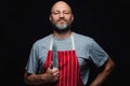 Professional fishmonger or butcher in grey t-shirt and red and white stripe classic apron on a black background. Bold male with