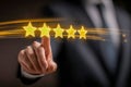 Businessman in suit selecting a glowing five-star rating with a futuristic digital interface symbolizing customer satisfaction and Royalty Free Stock Photo