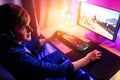 Gamer playing computer games online with headphones, in a room with neon light