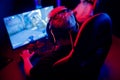 Professional gamer playing online games tournaments pc computer with headphones, Blurred red and blue background