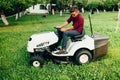 Professional Gardner trimming and landscaping garden using a ride on lawn mower