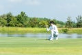 Professional Golfer asian man playing aiming shot for putting ball on the hole with club on green course.  Hobby in holiday and va Royalty Free Stock Photo