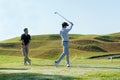 Professional golfer asian two man approach on the tee off for swing and hitting golf ball and looking fairway in course. Hobby in Royalty Free Stock Photo