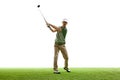 Professional golfer in casual attire in mid-swing with driver on artificial turf against white studio background. Royalty Free Stock Photo