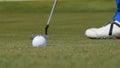 Professional golfer putting ball into the hole. Golf ball by the edge of hole with player in background on a sunny day Royalty Free Stock Photo