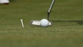 Professional golfer putting ball into the hole. Golf ball by the edge of hole with player in background on a sunny day Royalty Free Stock Photo