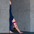 Professional gymnast doing warming-up stretching exercise performing standing split against wall in studio