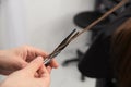 Professional hair stylist holding comb and hot thermal scissors cutting tips of long straight hair lock closeup Royalty Free Stock Photo