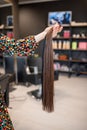 Professional hairdresser demonstrating hair samples for extension in beauty salon