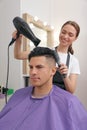 Professional hairdresser drying client`s hair in salon Royalty Free Stock Photo