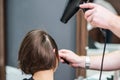 Professional hairdresser is drying female hair at hair salon. Royalty Free Stock Photo