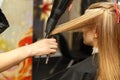 Professional hairdresser dyeing hair of her client in salon. Haircutter dry hair with hairdrier. Selective focus.