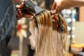 Professional hairdresser dyeing hair of her client in salon. Haircutter dry hair with hairdrier. Selective focus.