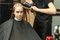 Professional hairdresser dyeing hair of her client in salon. Haircutter dry hair with hairdrier. Selective focus.