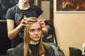 Professional hairdresser dyeing hair of her client in salon. Haircutter dry hair with hairdrier. Selective focus.