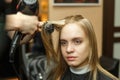 Professional hairdresser dyeing hair of her client in salon. Haircutter dry hair with hairdrier. Selective focus.