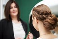 Professional hairdresser making coiffure for female client in front of big mirror. Work process in beauty studio. Bride getting Royalty Free Stock Photo