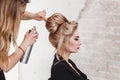 Hairdresser using hair spray on client business woman hair at beauty salon