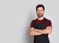 Professional hairdresser wearing apron with on light grey background, space for text