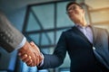 A professional handshake after a successful group collaboration meeting after in a modern corporate office. Young man