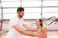 Professional handsome instructor showing woman how to play tennis