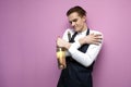 Professional handsome waiter in uniform hugs two bottles of red and white wine on a pink background, concept love of alcohol, copy Royalty Free Stock Photo