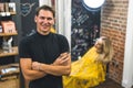 Professional happy male hairdresser in the black t-shirt holding scissors in the professional hair salon. Blonde female Royalty Free Stock Photo