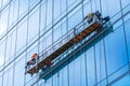 Professional high rise window cleaning service workers in gondola. Two workers use specialized equipment to access and clean glass Royalty Free Stock Photo