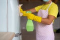 Professional house cleaning. A maid girl in the same rubber gloves and an apron wipes the refrigerator. Royalty Free Stock Photo