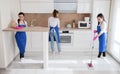 Professional house cleaning. Three beautiful girls are cleaning the kitchen. The girl washes the floor. Royalty Free Stock Photo