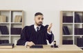 Professional and impartial serious male judge addresses defendant or his lawyer during trial.