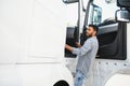 Professional indian truck driver entering his truck long vehicle. Loving his job. Transportation services. Royalty Free Stock Photo