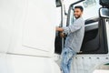 Professional indian truck driver entering his truck long vehicle. Loving his job. Transportation services. Royalty Free Stock Photo