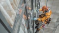 Industrial climber in helmet and gloves washes windows on tall building top view Royalty Free Stock Photo